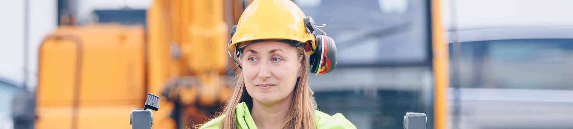 woman operating excavator with safety wear on