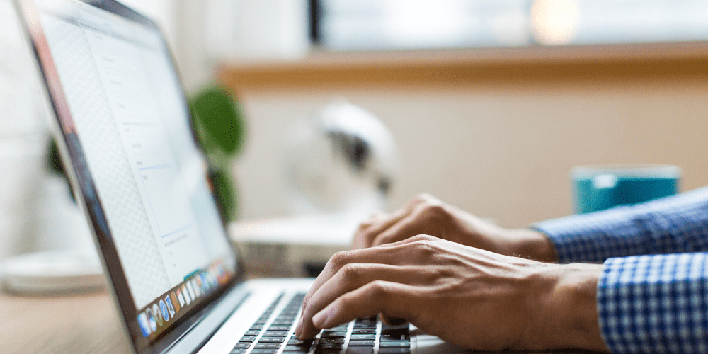 man on mac laptop managing a remote workforce